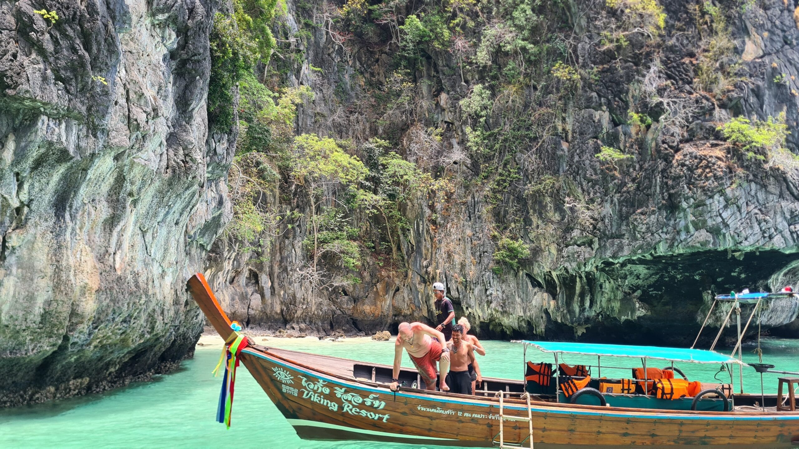 Longtail boat in turquoise water beneath Krabi limestone cliffs