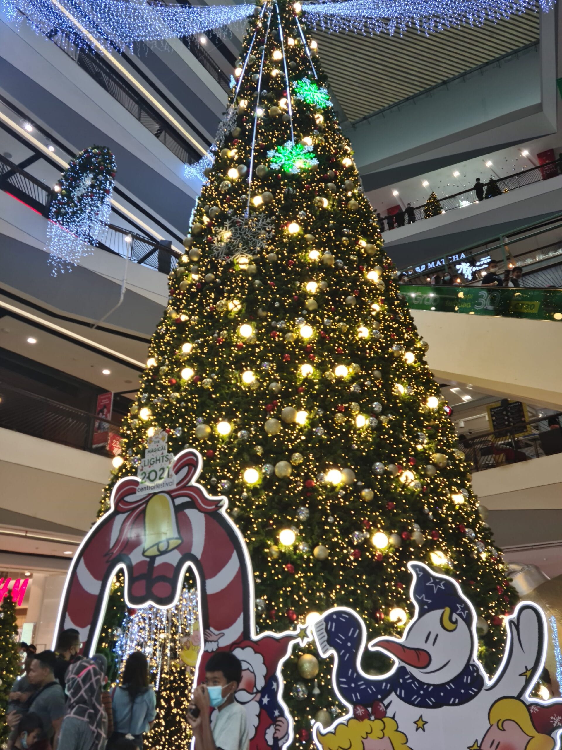 Tall decorated Christmas tree and holiday lights inside a Thai shopping mall