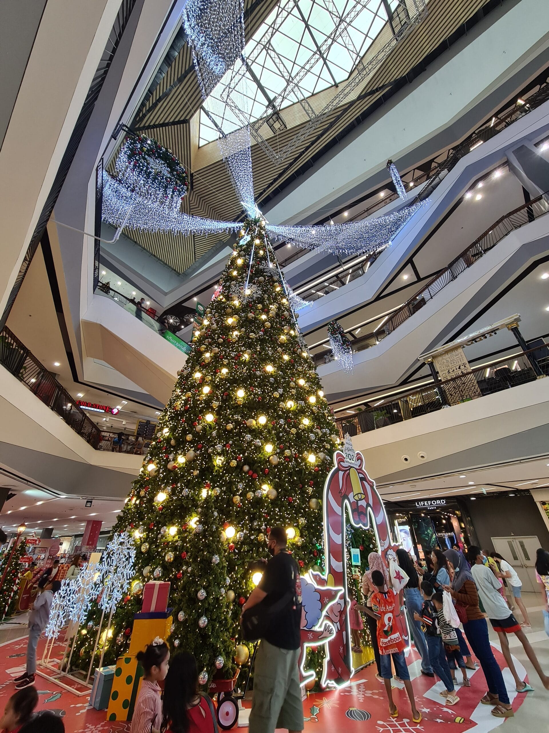 Nana standing beneath a massive Christmas tree in Thailand