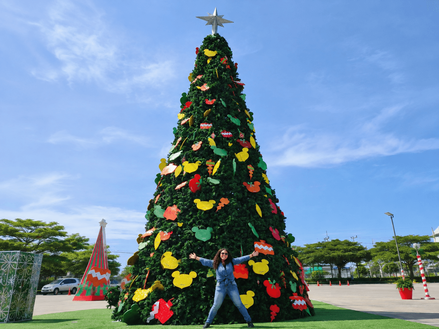 Nana standing beneath a giant outdoor Christmas tree in Thailand