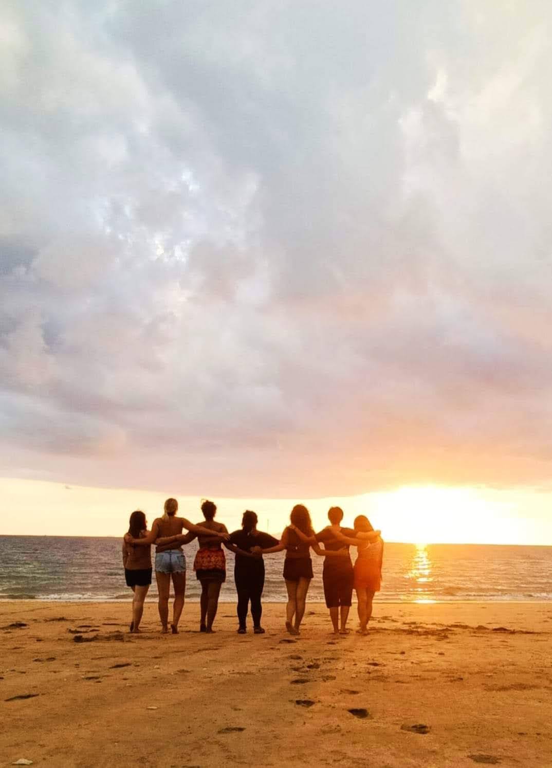 Group of friends standing together on a beach at sunset