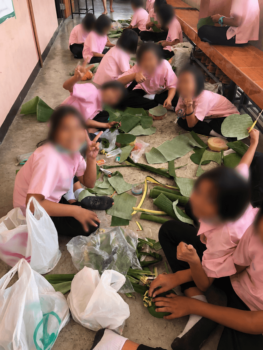 Close-up of a handmade krathong with identifying school text and symbols blurred for privacy