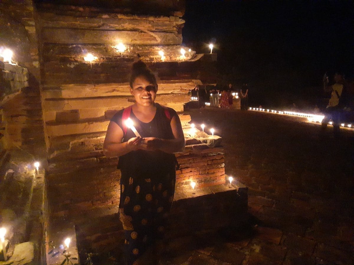 Nana holding a candle near a temple during Thadingyut in Myanmar