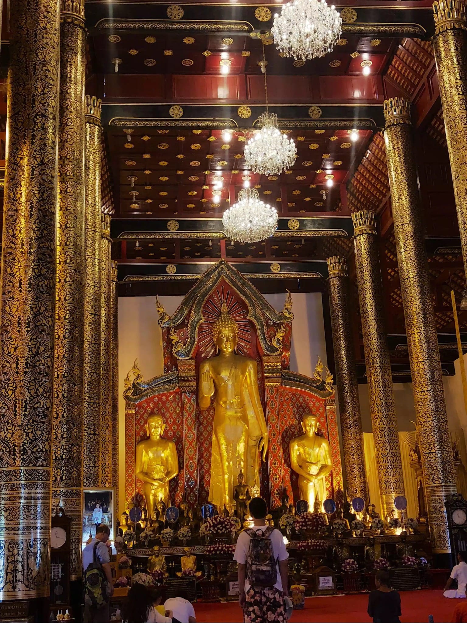 Golden Buddha statues and ornate columns inside a Chiang Mai temple