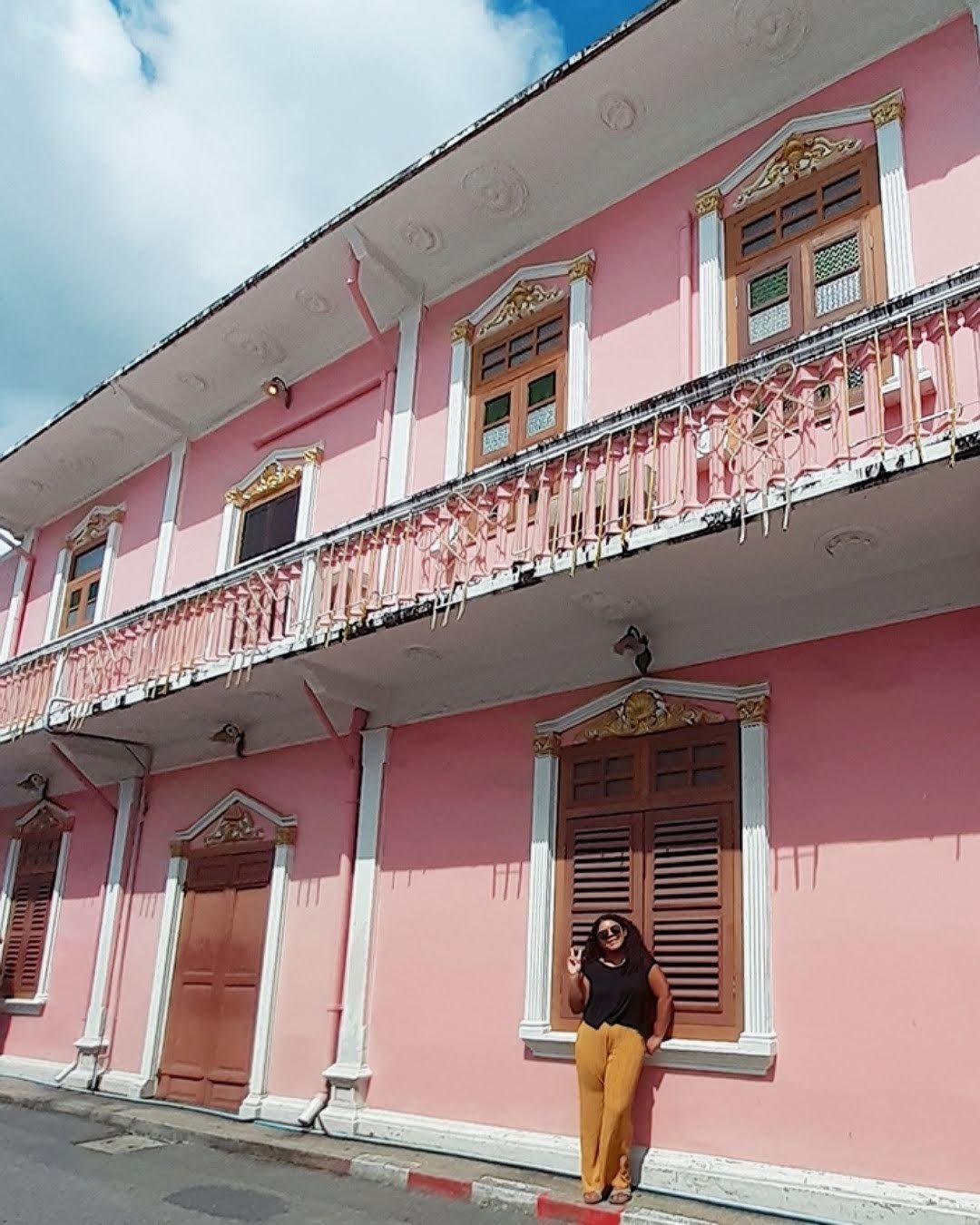 Nana standing in front of a pink historic building in Phuket Town in 2019